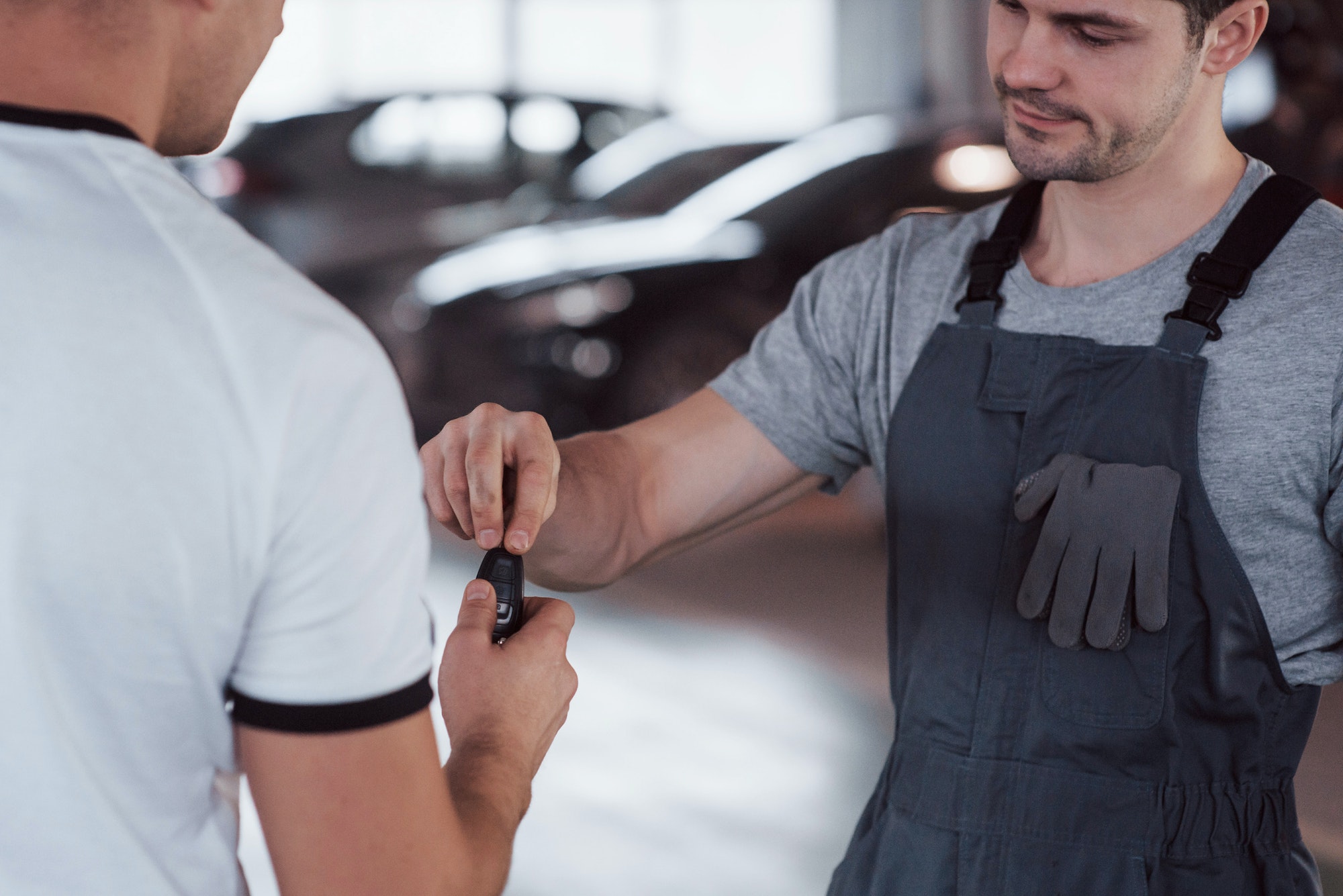 Mechanic gives keys to the owner of the repaired car in the workshop