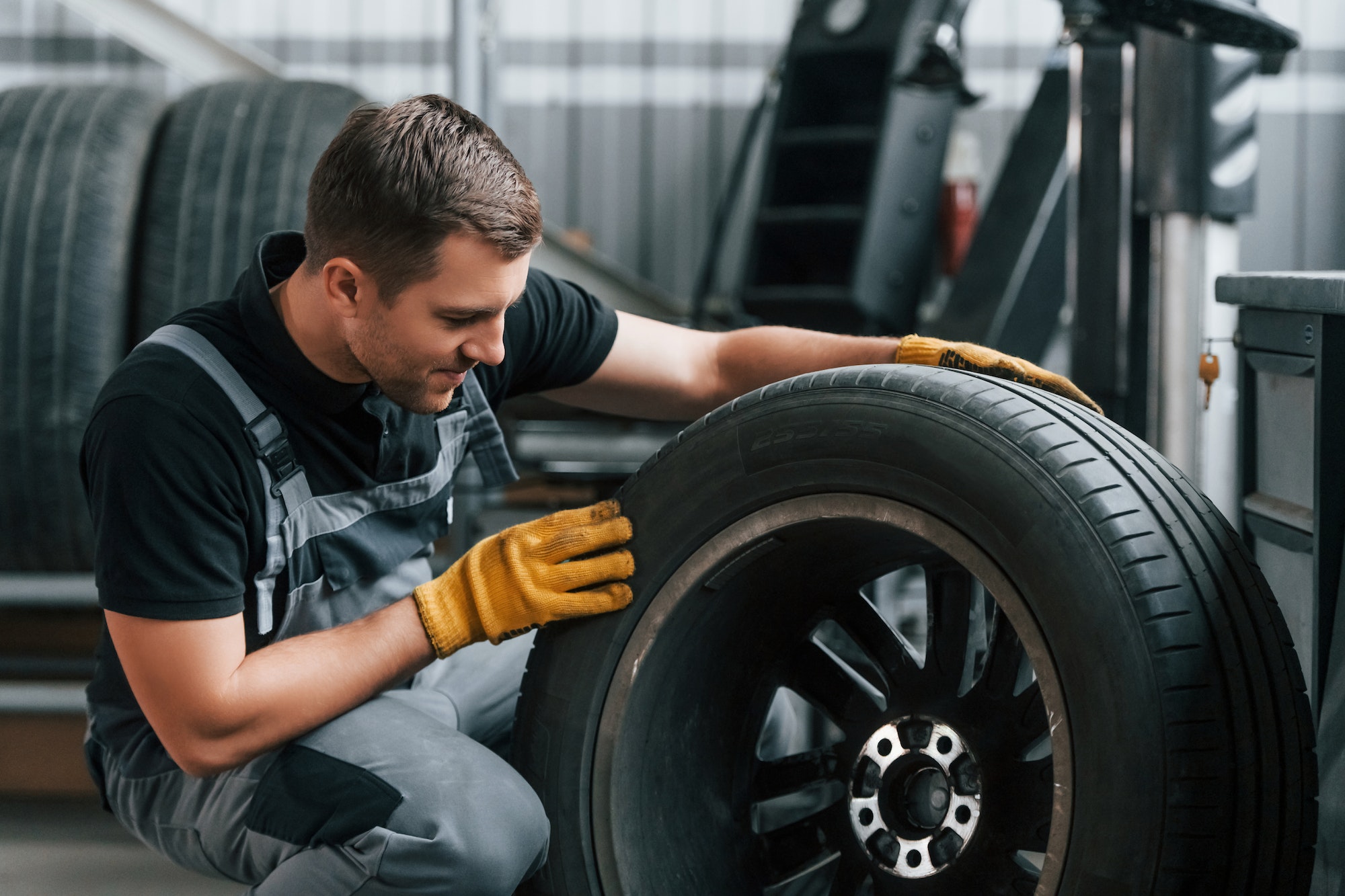 Replacement of the old tire. Man in uniform is working in the auto service